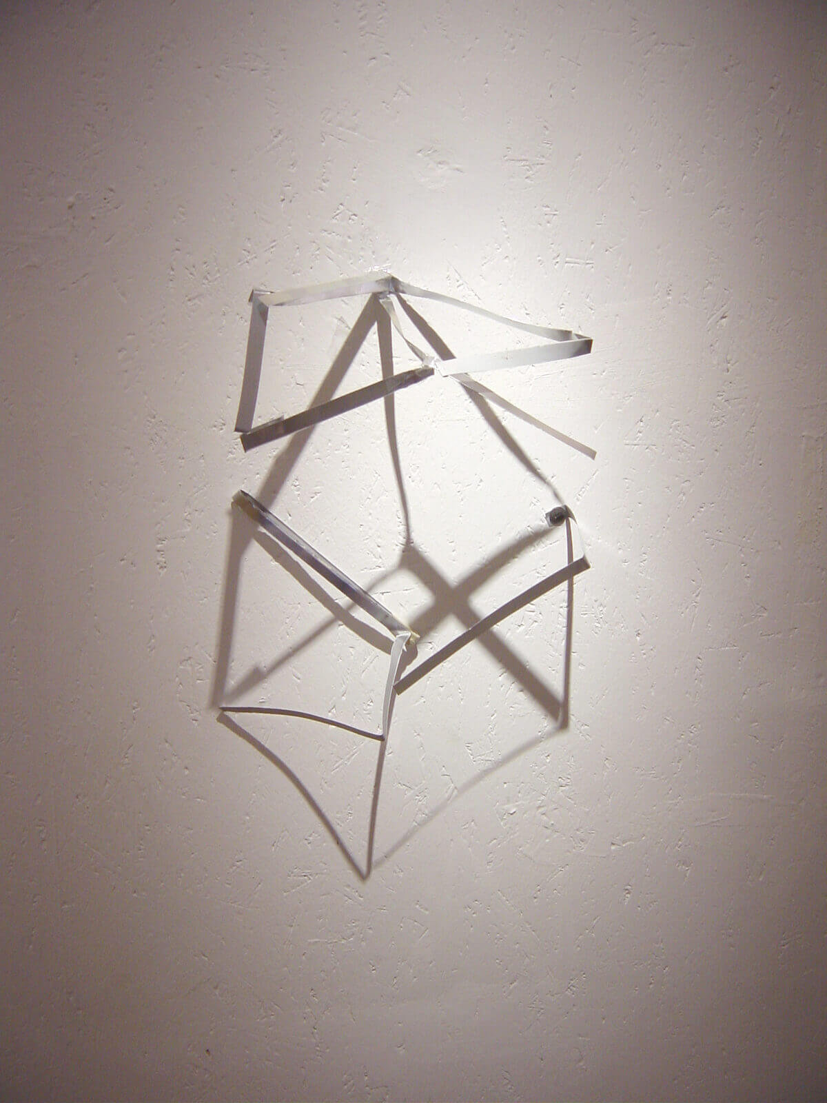 Wall-mounted installation of bent metal strips arranged in an abstract geometric formation, casting shadows.