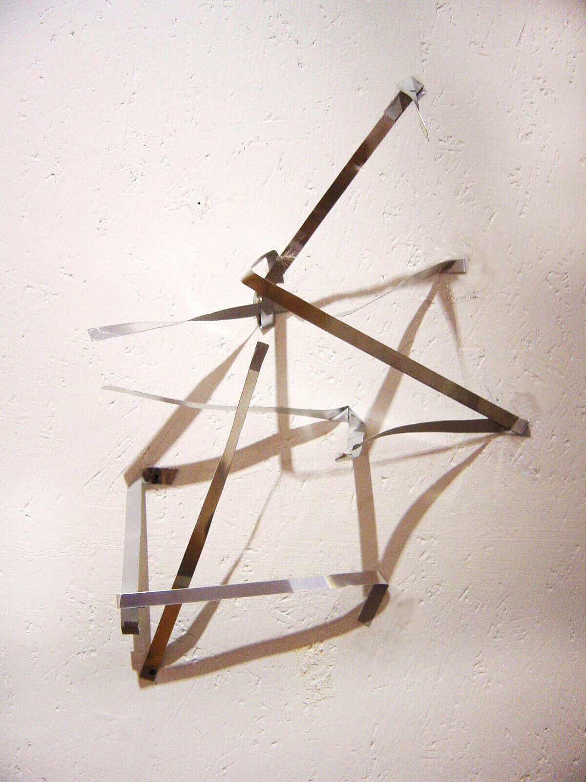 Geometric wall installation made of metal strips arranged in an open angular structure.