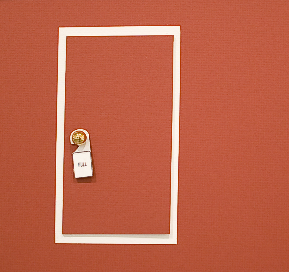 Architectural model, miniature door with white frame and terracotta-colored surface, close-up detail showing brass doorknob and "PULL" sign, matching terracotta walls.