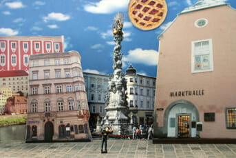 Photomontage collage urban square buildings and architectural landmarks in Linz, layered composition with floating graphic elements and monument, flat graphic presentation.